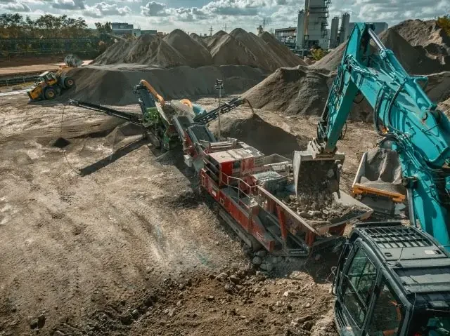 Brecher und Bagger vor den Haufwerken der Recyclinganlage – Einsatz der B&B GmbH in Bielefeld