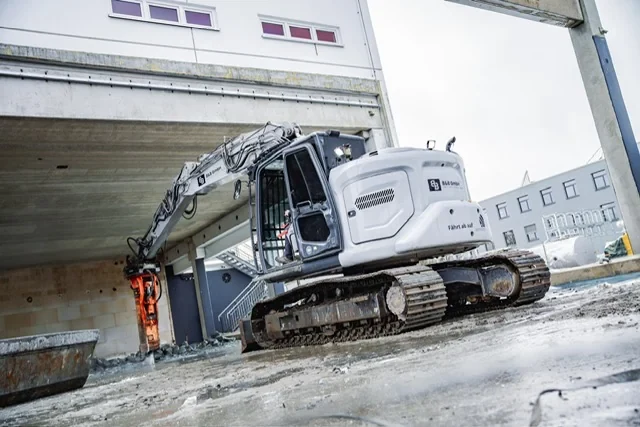 Kettenbagger mit Hydraulikhammer arbeitet unter einem Brückenbauwerk