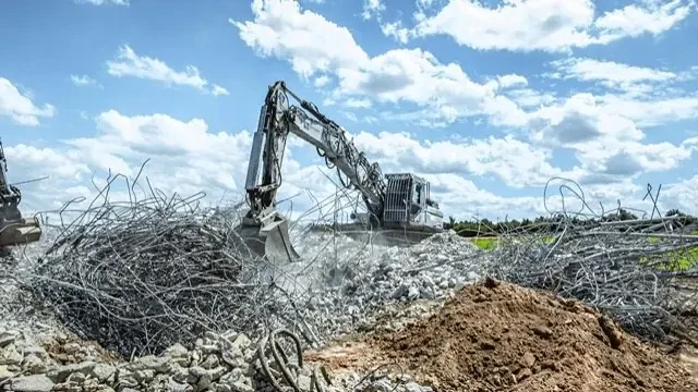 Abbruchzange trennt die Bewehrung eines Stahlbetonbauteils